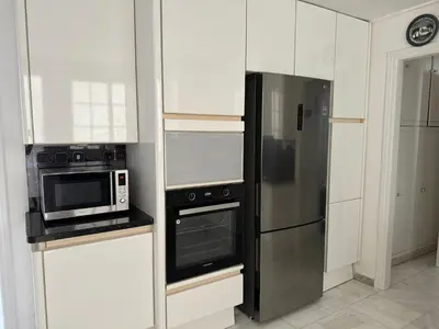 a kitchen with white cabinets and a stainless steel refrigerator at Vouliagmeni Seaside Escape in Athens