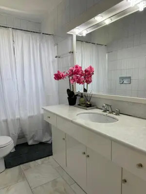 a bathroom with a sink and a mirror and pink flowers at Vouliagmeni Seaside Escape in Athens