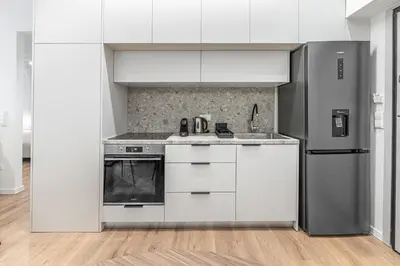 a kitchen with white cabinets and a stainless steel refrigerator at Phaedrus Living Prosperity Residences Paradise in Athens