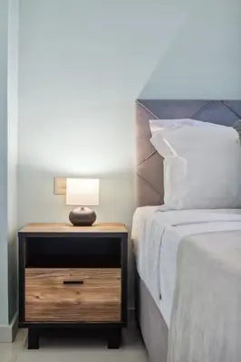 a bed with a night stand with a lamp on it at Penthouse Sauna & Jacuzzi in Glyfada in Athens