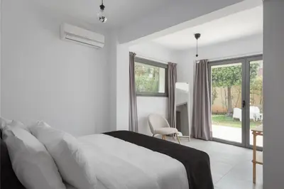 a white bedroom with a bed and a chair at Grand Apollon Villa in Sounio