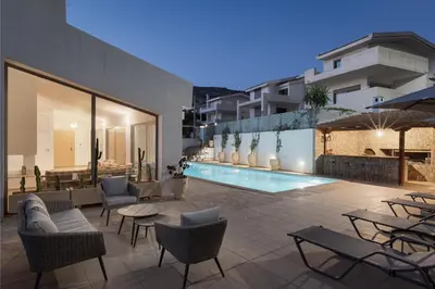 a patio with chairs and tables and a swimming pool at Grand Apollon Villa in Sounio