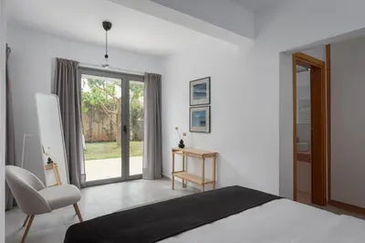 a bedroom with a bed and a chair and a window at Grand Apollon Villa in Sounio