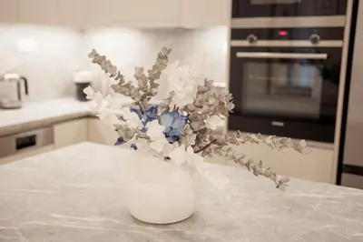 a white vase with flowers sitting on a kitchen counter at J&B Apartment in Athens