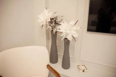 two vases with flowers on a table next to a chair at J&B Apartment in Athens
