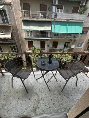 two chairs and a table on a balcony with a building at Check Point - Acropolis Retro in Athens
