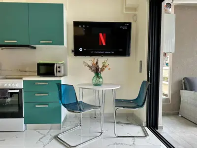 a kitchen with a table with a tv on the wall at Sky Suite Apartments - Cloud9 in the City in Athens