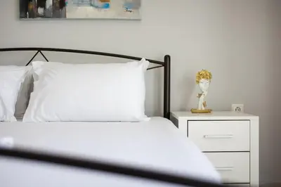a bedroom with a white bed and a white night stand at Pleasant Apartment Near To Acropolis in Athens