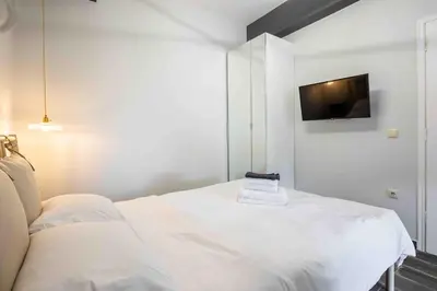 a bedroom with a white bed with a tv on the wall at Holiday close to Acropolis 1 in Athens