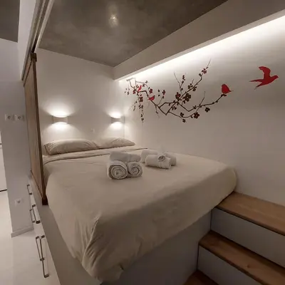 a bedroom with a bed with two towels and birds on the wall at Lux Studio in Ilioupoli, 20 min from Acropolis in Athens