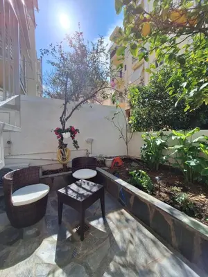 a patio with two chairs and a table and a tree at Lux Studio in Ilioupoli, 20 min from Acropolis in Athens