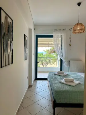 a bedroom with a bed and a door to a balcony at Saronida365 Sea & Sunset view in Saronida