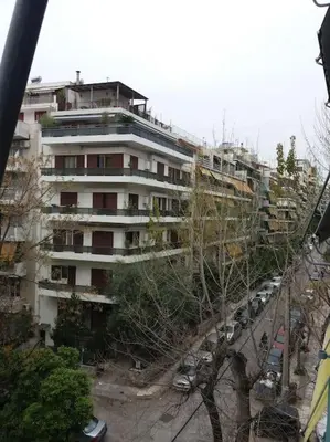 a tall white building with cars parked in front of it at Urban apt Metro line 3 1min walk in Athens