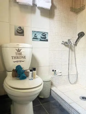 a bathroom with a toilet with the throne sign on it at Medusa Apartment in Artemida