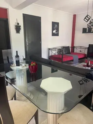 a living room with a glass table and a bed at Medusa Apartment in Artemida