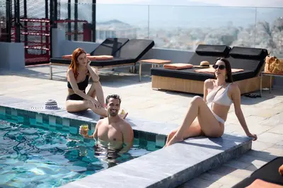 a man and two women sitting in a swimming pool at President Hotel Athens in Athens