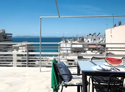 a table and chairs on a balcony with a view of the ocean at Wonder Apartment over the Sea in Athens
