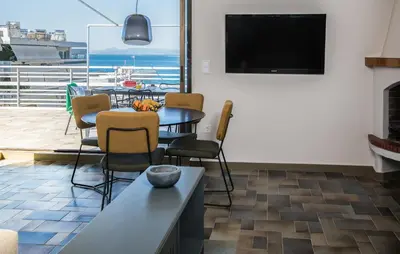 a living room with a table and chairs and a television at Wonder Apartment over the Sea in Athens