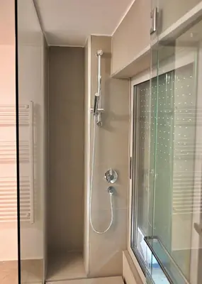 a shower with a glass door next to a window at Bright and comfy apartment in the heart of Athens in Athens