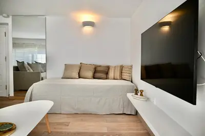 a white bedroom with a bed and a tv at Bright and comfy apartment in the heart of Athens in Athens