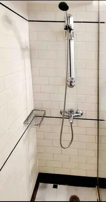 a shower with a hose in a white tiled bathroom at Alimos Cozy Studio in Athens