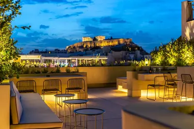 a rooftop patio with tables and chairs at night at The Dorians in Athens
