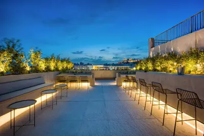a rooftop patio with chairs and lights at night at The Dorians in Athens