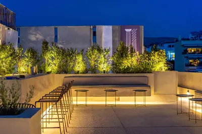 a rooftop patio with chairs and lights at night at The Dorians in Athens