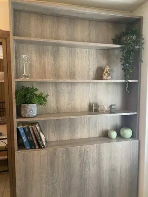 a wooden book shelf with books and plants on it at George's Apartment in Athens