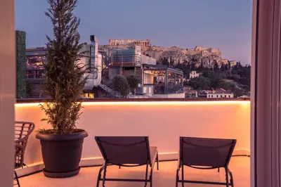 a balcony with two chairs and a potted plant at Elegant 2BR with Jacuzzi & Acropolis View in Athens
