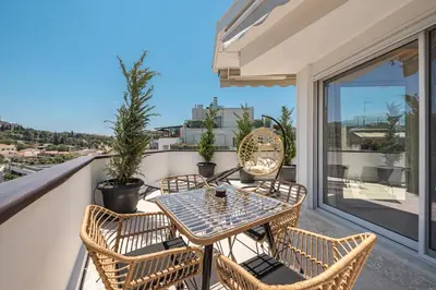 a patio with a table and chairs on a balcony at Elegant 2BR with Jacuzzi & Acropolis View in Athens