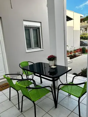 a black table and two green chairs on a patio at Flower House in Koropi-near airport in Koropíon