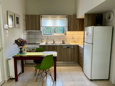 a kitchen with a table and a white refrigerator at Flower House in Koropi-near airport in Koropíon