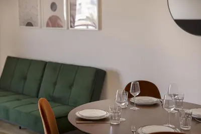 a dining room with a table and a green couch at Afroditis58-64 in Athens