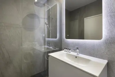 a bathroom with a sink and a shower with a mirror at Afroditis58-64 in Athens