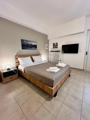 a bedroom with a large bed and a flat screen tv at Lia's luxury apartment - near airport in Koropíon