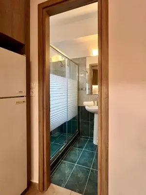 a bathroom with a shower and a sink and a mirror at Lia's luxury apartment - near airport in Koropíon
