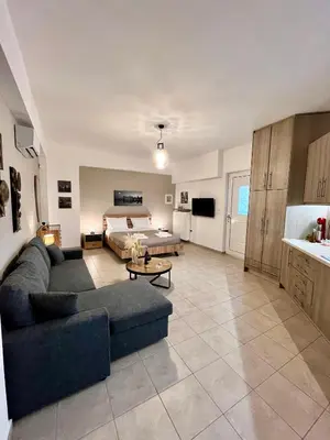 a large living room with a couch and a bed at Lia's luxury apartment - near airport in Koropíon