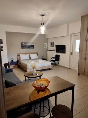 a room with a bed and a living room with a table at Lia's luxury apartment - near airport in Koropíon