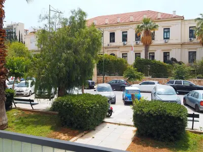 a parking lot with cars parked in front of a building at Athens White House in Athens