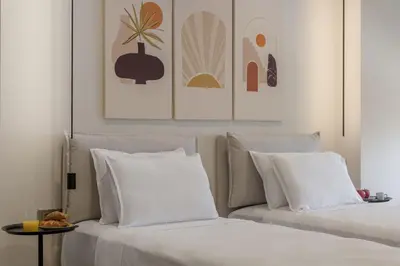 two beds with white pillows sitting next to a table at Acropolis View Plunge Pool Loft in Athens