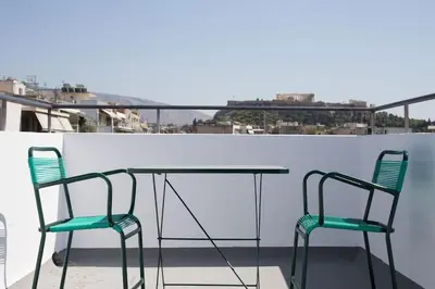 two chairs and a glass table on a balcony at A comfortable small studio nearby Acropolis 2 in Athens