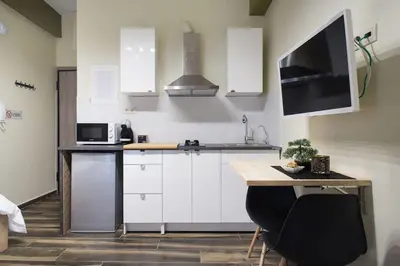 a kitchen with white cabinets and a table and a tv at A comfortable small studio nearby Acropolis 2 in Athens