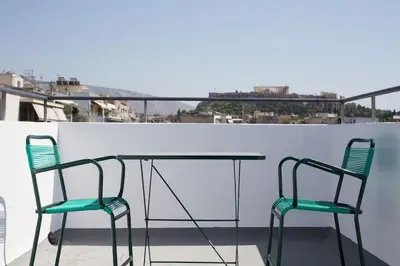 two chairs and a glass table on a balcony at A comfortable small studio nearby Acropolis 3 in Athens