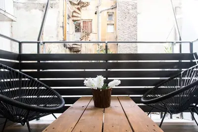 a wooden table with two chairs and a vase with flowers at A comfortable small studio nearby Acropolis 4 in Athens