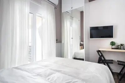 a white bedroom with a bed and a television at A comfortable small studio nearby Acropolis 4 in Athens