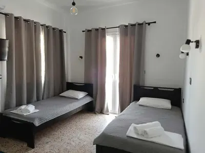 two beds sitting in a room with a window at Διαμέρισμα 1 ΣΤΗΝ ΑΓΙΑ ΜΑΡΙΝΑ in Agia Marina Aegina
