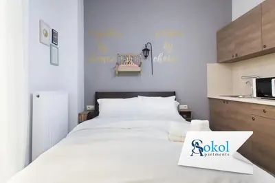 a bedroom with a large white bed and a kitchen at A comfortable small studio nearby Acropolis 201 in Athens