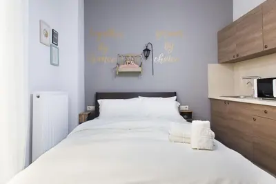 a bedroom with a large white bed and a kitchen at A comfortable small studio nearby Acropolis 201 in Athens