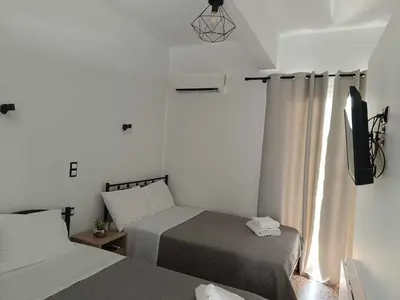 a hotel room with two beds and a television at Διαμέρισμα 2 ΣΤΗΝ ΑΓΙΑ ΜΑΡΙΝΑ in Agia Marina Aegina